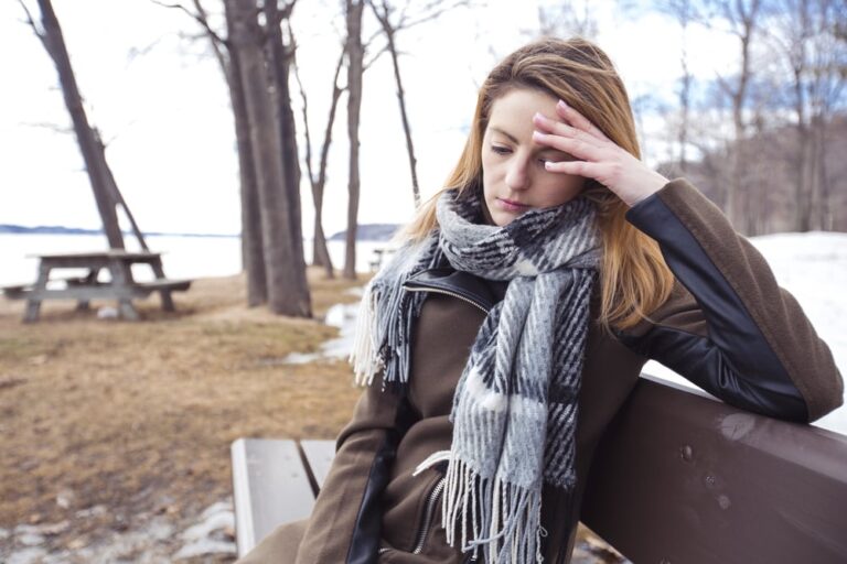 mujer triste sentada sola en un banco del parque
