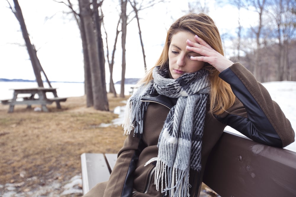 sad woman sitting on bench in park alone