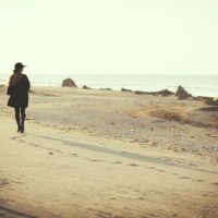 mujer triste caminando por la playa