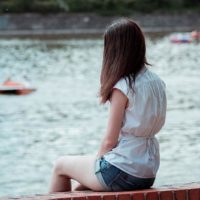 mujer sentada sola frente al agua