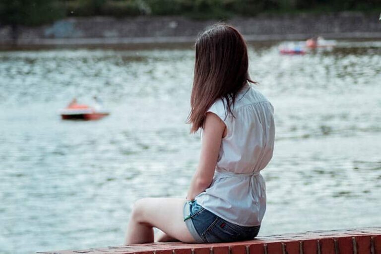 woman sitting alone in front of water