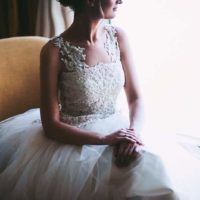 the woman in the wedding dress sitting beside window and looking out