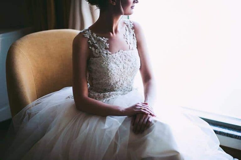 the woman in the wedding dress sitting beside window and looking out