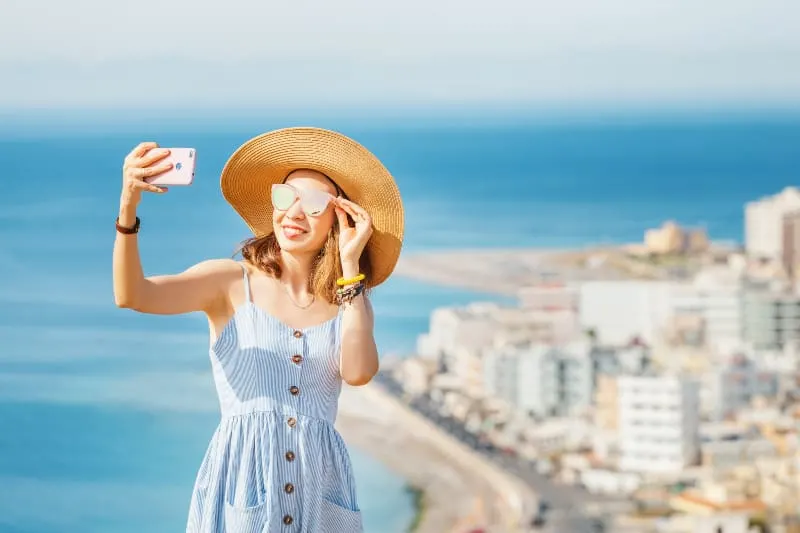 A young stylish girl in a big hat taking selfie
