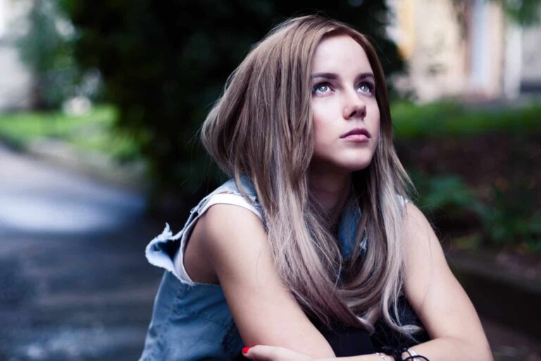 a beautiful girl is sitting outside and looking up