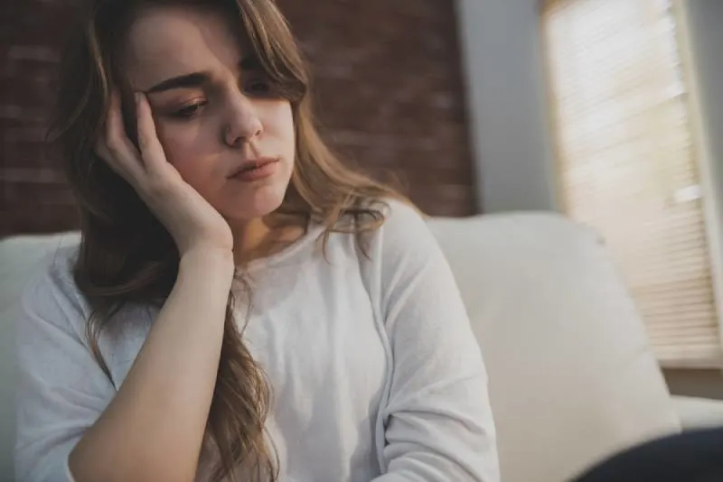 Angry woman sitting on the couch and holding her head in the living room