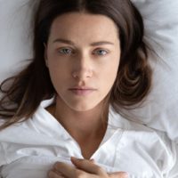 sad woman lying in bed and staring at one point