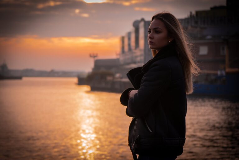 a sad blonde at sunset standing by the sea