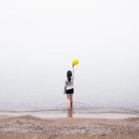 uma mulher de pé no mar com um balão na mão
