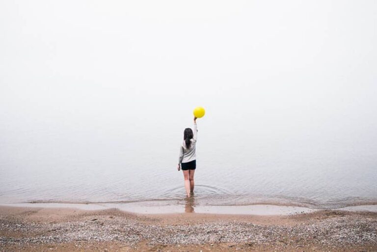 a woman standing in the sea with a balloon in her hand