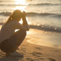 mujer preocupada sentada en la playa