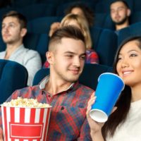 man holds popcorn and looking at his girlfriend in cinema