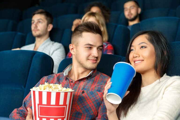 hombre sostiene palomitas y mirando a su novia en el cine