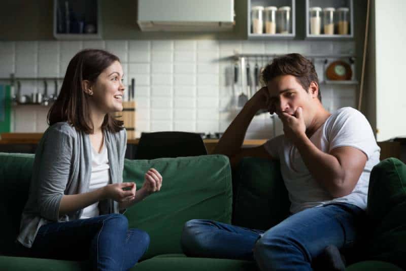 El joven bosteza y se aburre al escuchar hablar a la emocionada mujer