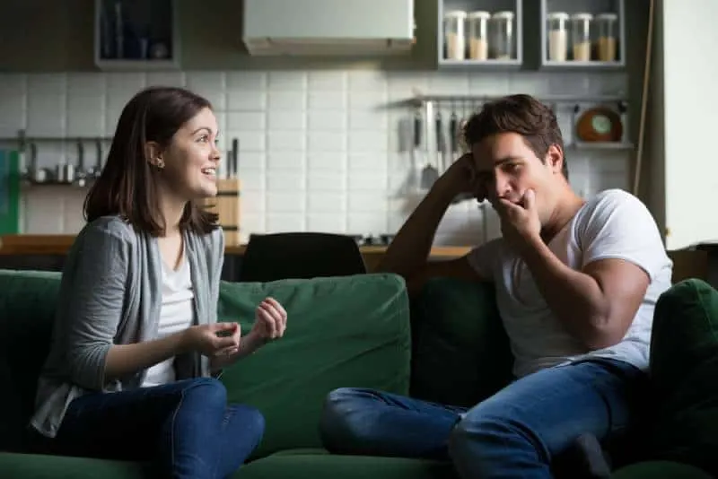 Young man yawns and is bored when he listens to the excited woman talking