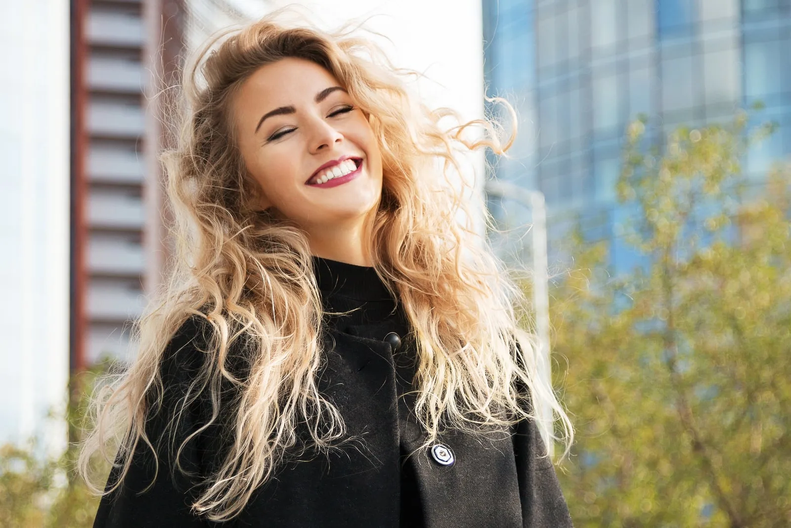 a portrait of a smiling blonde in a black coat