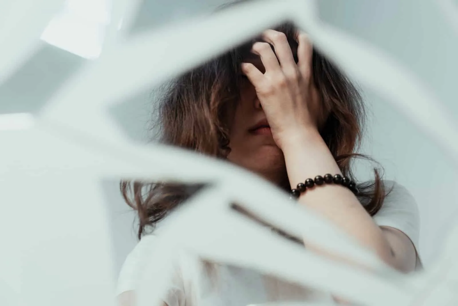 a reflection of a sad girl on a broken mirror
