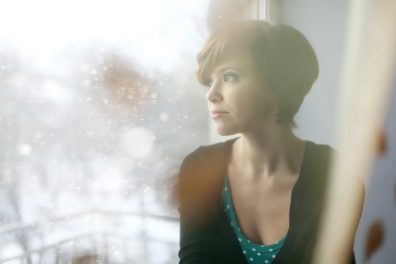 a short-haired woman looks out the window