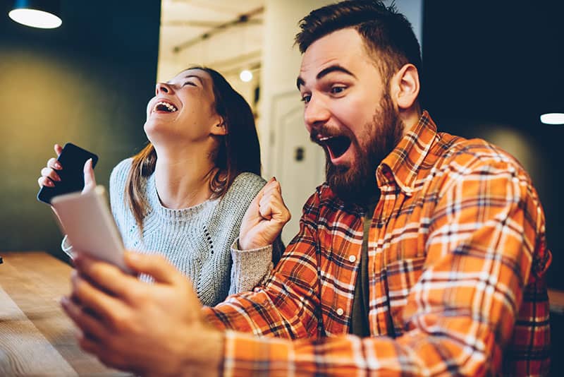 Gli hipster maschi e femmine eccitati gioiscono per la vincita di una lotteria su internet