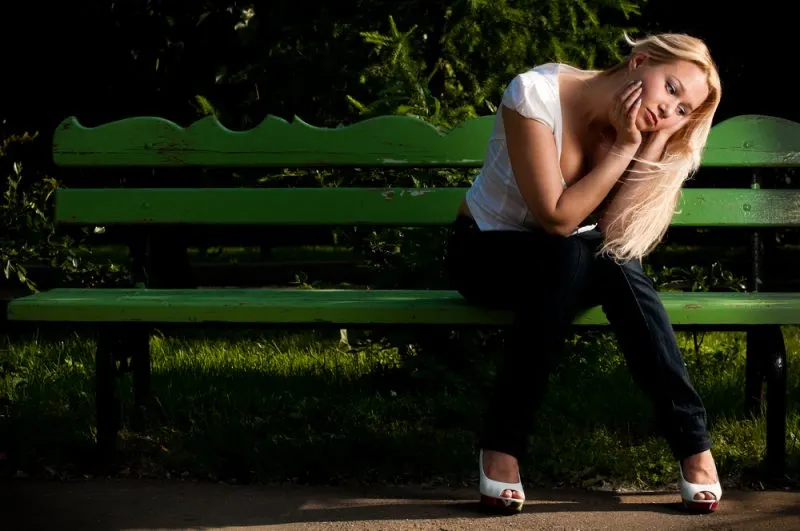 blond woman wearing white shirt sitting on the bench