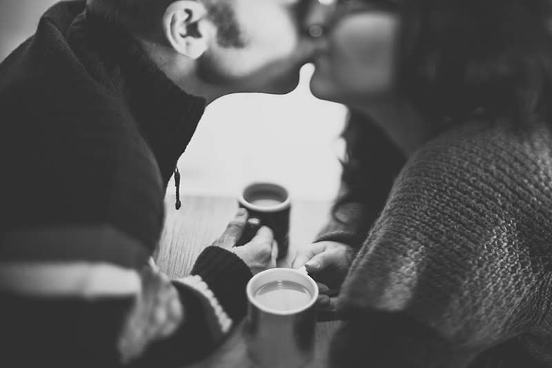 volto sfocato di persone che si baciano tenendo in mano una tazza di caffè