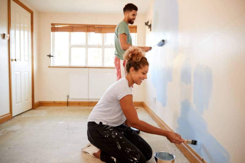 couple decorating room, painting wall in blue