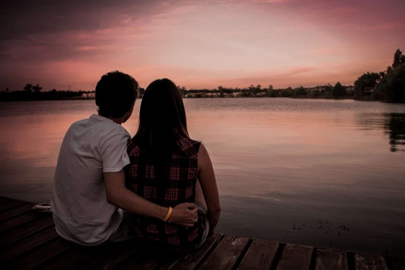 pareja sentada cerca del lago