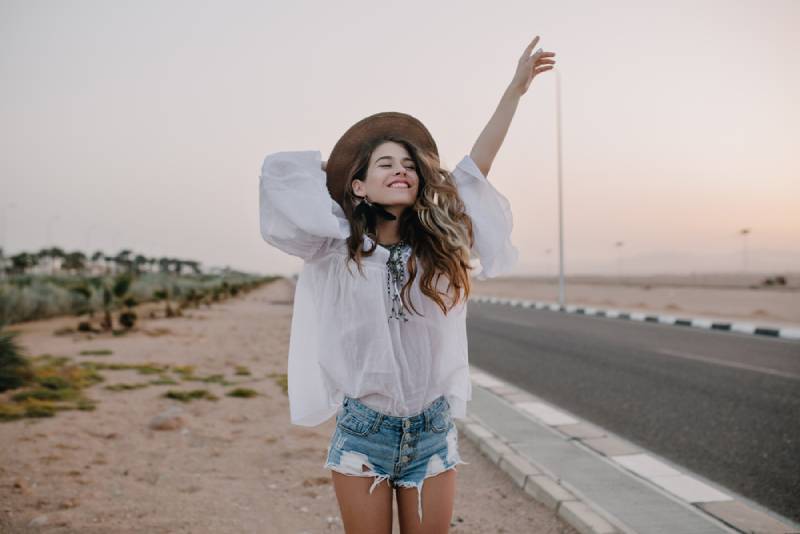 happy woman walking and raising her hand outside