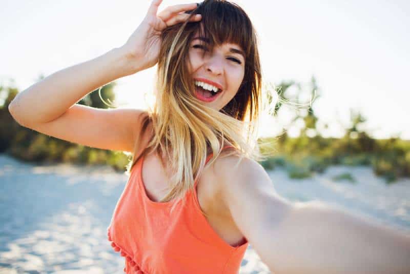 giovane donna felice che si scatta un selfie sulla spiaggia