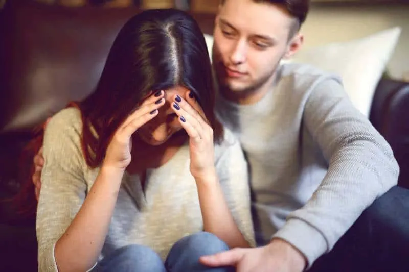 man comforting crying woman at home