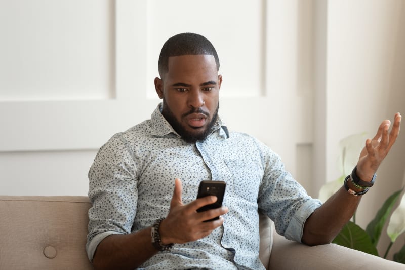 man looking at phone looks confused