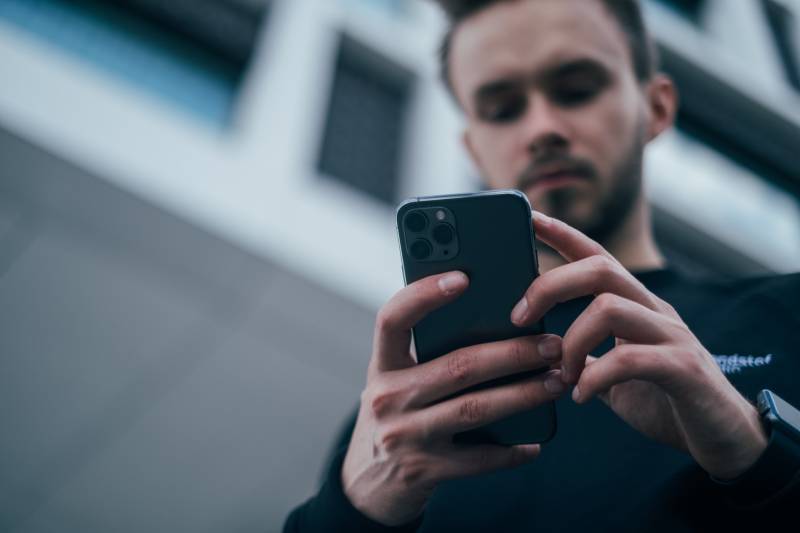 homem a olhar para o telemóvel no exterior