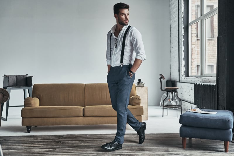 man wearing white shirt, blue pants and black shoes standing in living room