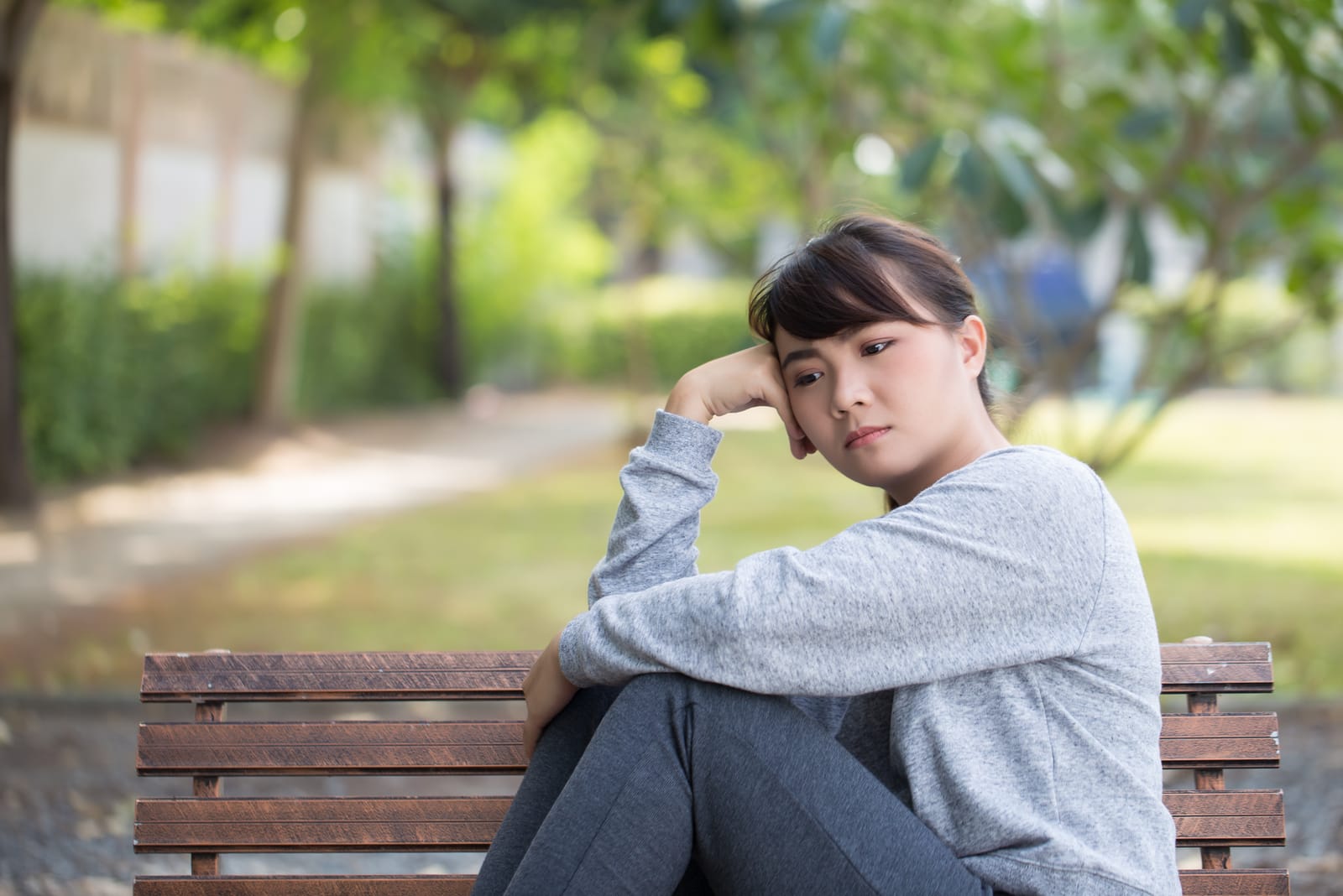 donna triste seduta su una panchina nel parco