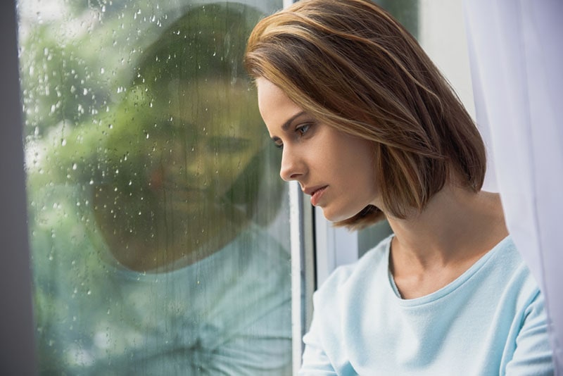 sad young woman looking through the window