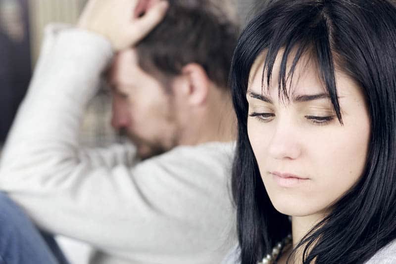 shallow focus on worried woman sitting next to upset man