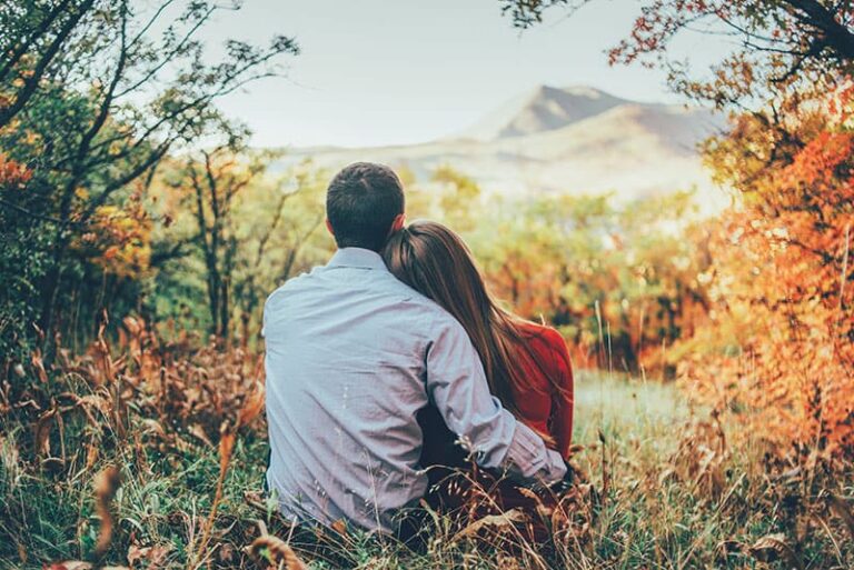 doce casal sentado na relva no meio da natureza