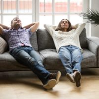 man and woman relaxing at home on sofa