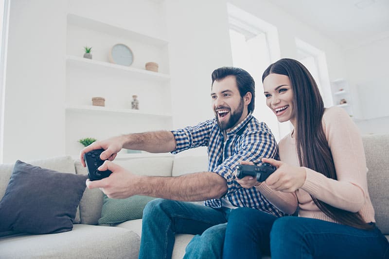 Retrato de alegre pareja activa disfrutando jugando a un videojuego