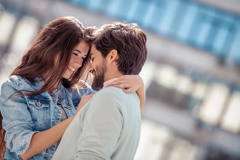 Happy young couple hugging and laughing outdoors. 