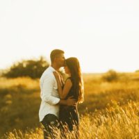 Pareja de jóvenes enamorados en un campo al atardecer