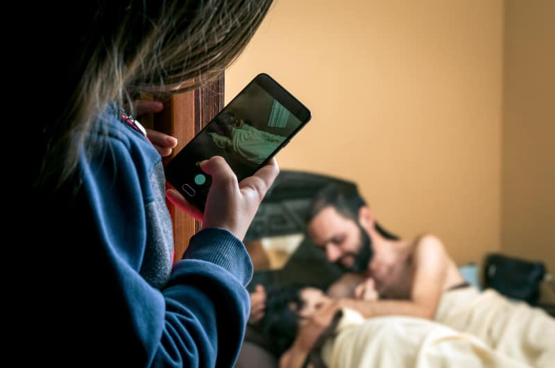 woman takes picture of couple in bed