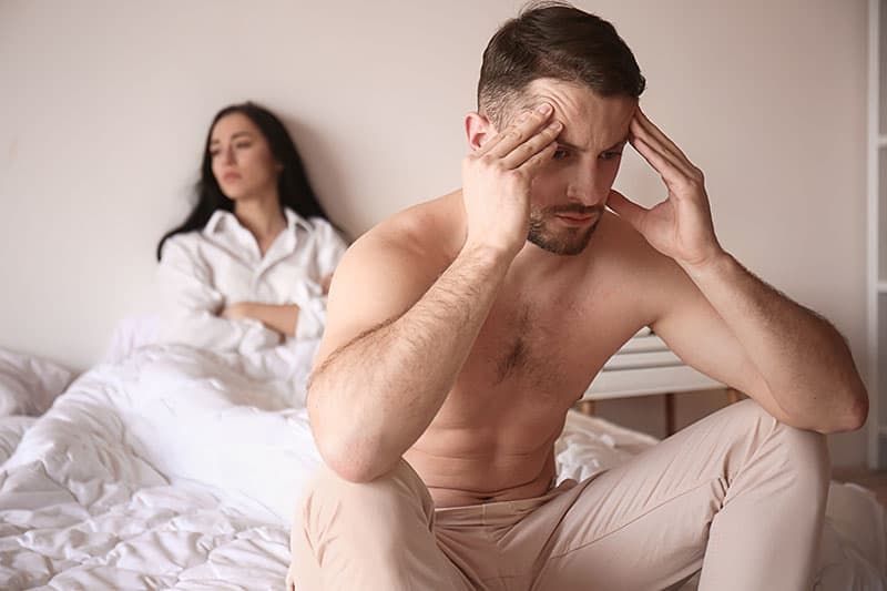 Young sad man sitting on bed after quarrel with wife