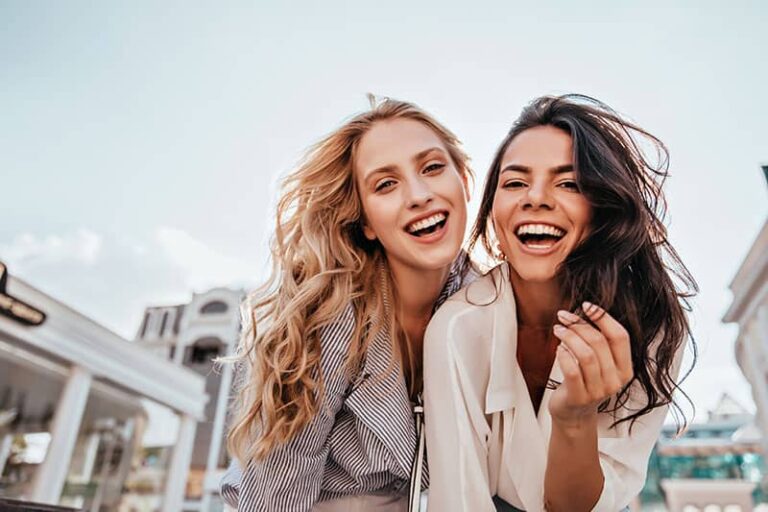 Appealing long-haired girls posing on sky background. Laughing ladies enjoying weekend together