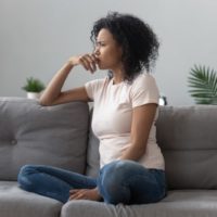 Sad thoughtful worried african american girl sit on sofa