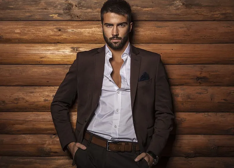 Portrait of young beautiful fashionable man against wooden wall.