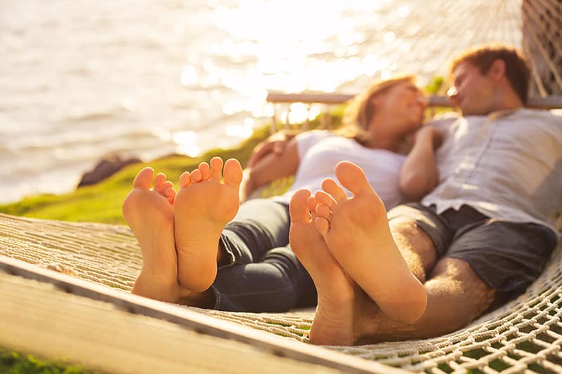 Romantic couple relaxing in tropical hammock at sunset, Shallow depth of field, focus on feet. 