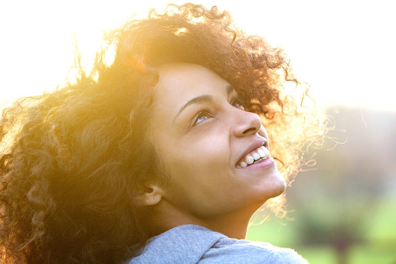 Retrato de cerca de una hermosa joven afroamericana sonriendo y mirando hacia arriba