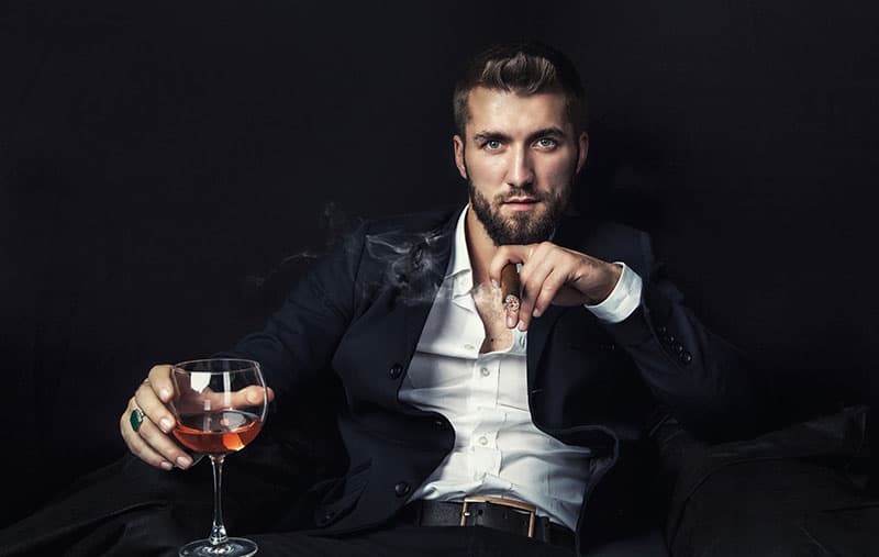 Hombre atractivo con un puro y un vaso de vino en las manos