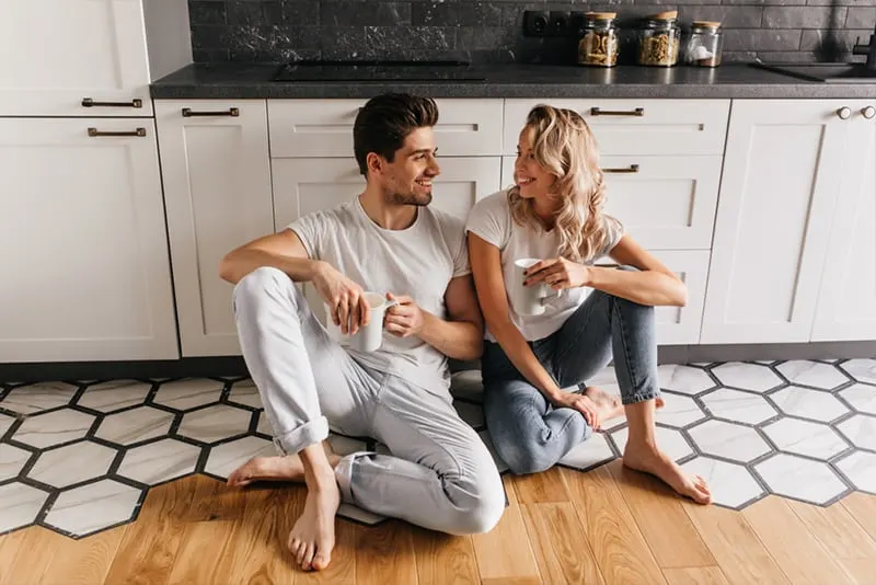 Beautiful couple sitting on the kitchen floor talking and looking at each other